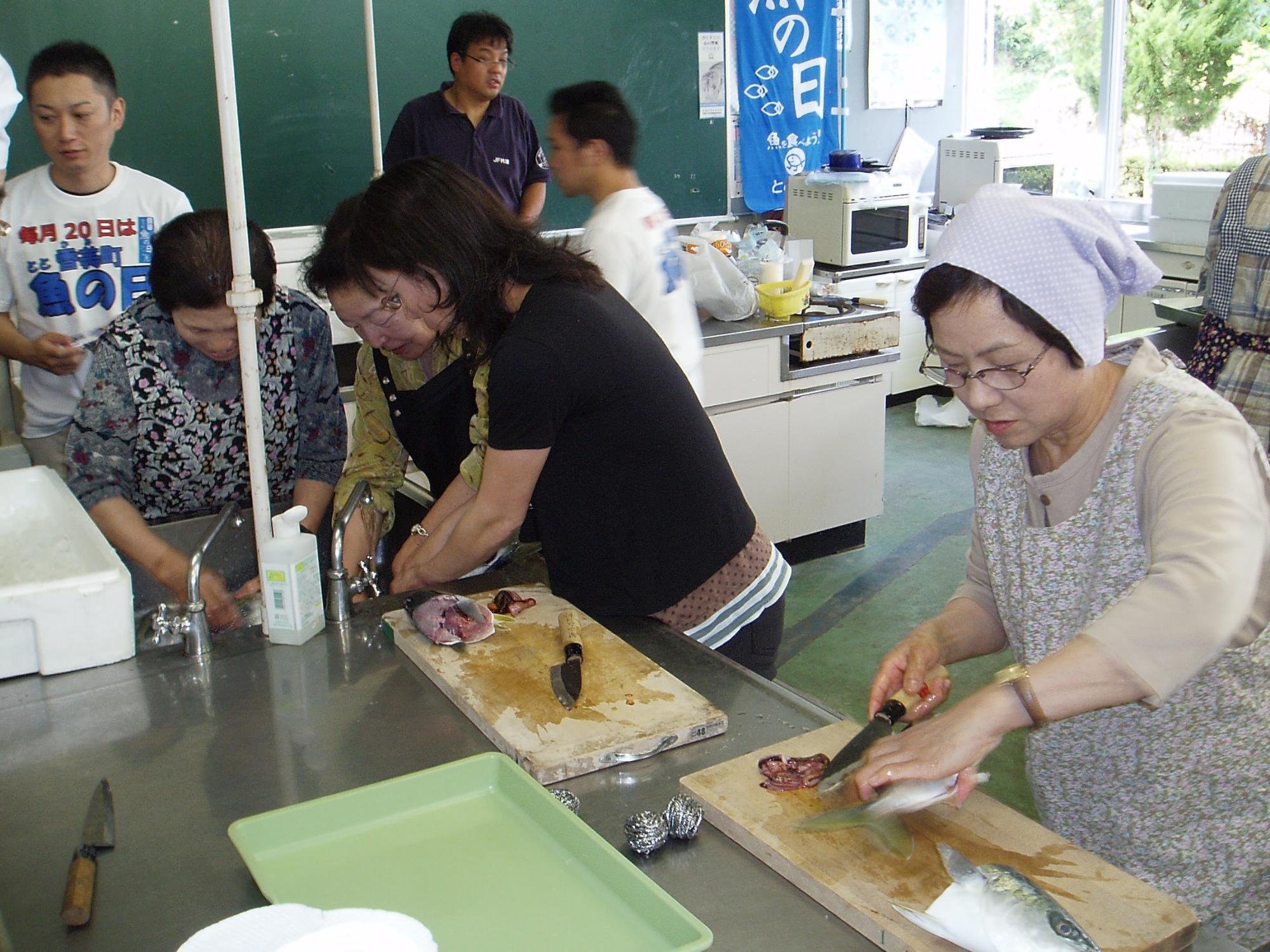 調理室で参加者がまな板の上の魚をさばいている写真