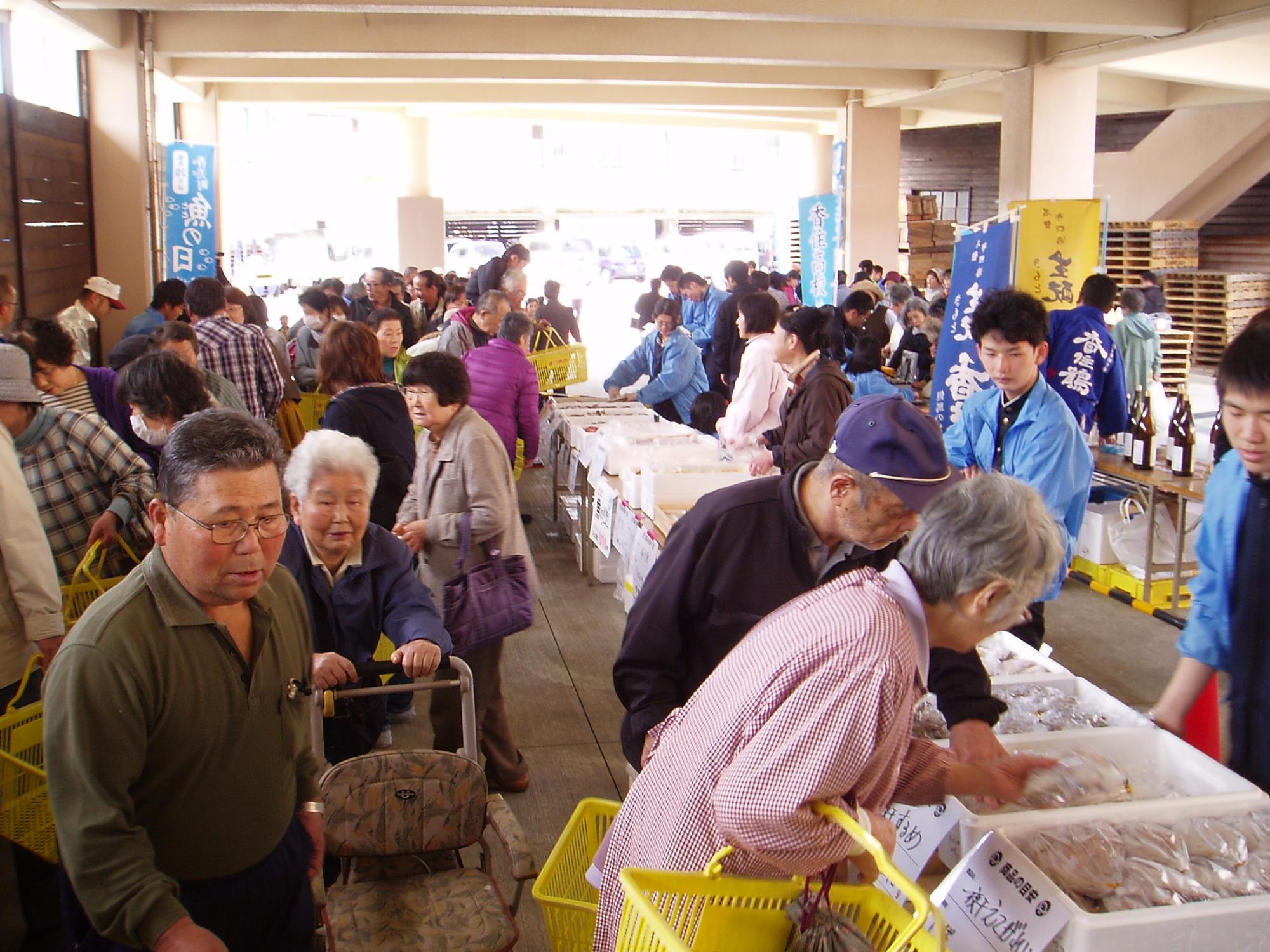 魚の直売コーナーで多くの人が買い物をしている写真