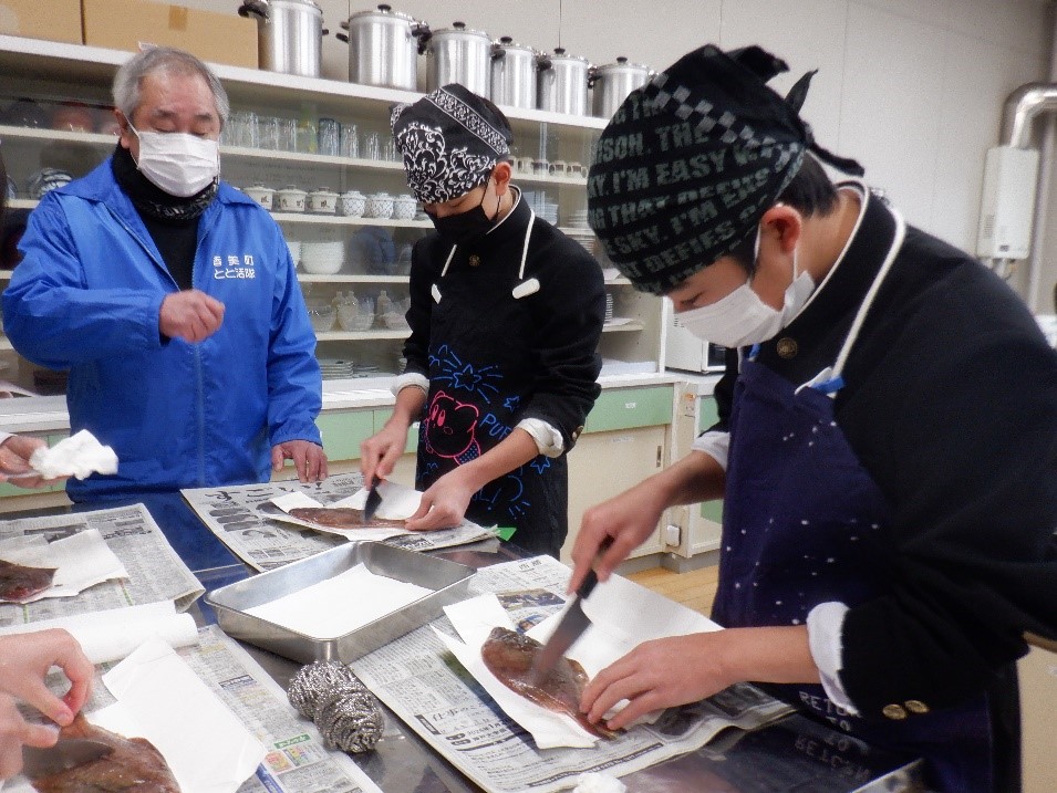 指導を受けて生徒たちが魚をおろしている様子の写真