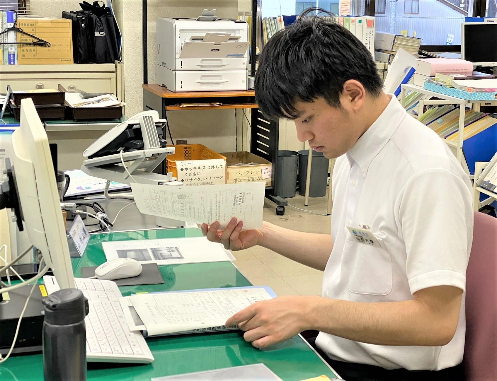 椅子に座り事務机の上の書類を確認している町役場職員の写真