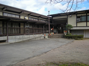 青空の下に横に長い建物が2棟建っている写真