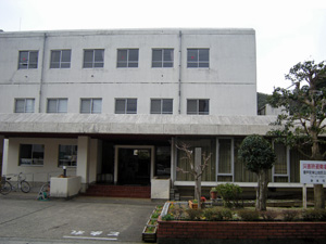 灰三階建ての白い建物の玄関を正面から撮影した写真