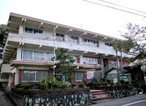 曇り空の下白い外壁の3階建ての建物が建っている写真