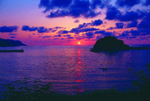 全体が赤と青のグラデーションに染まった海に浮かぶ島の写真