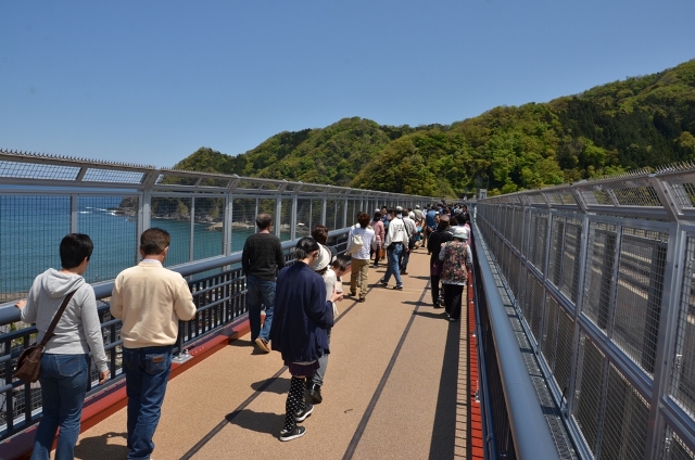 海横の橋を歩くたくさんの人たちの写真