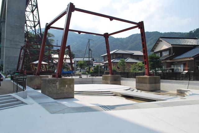 赤い鉄骨の下に作られた小さな広場の写真