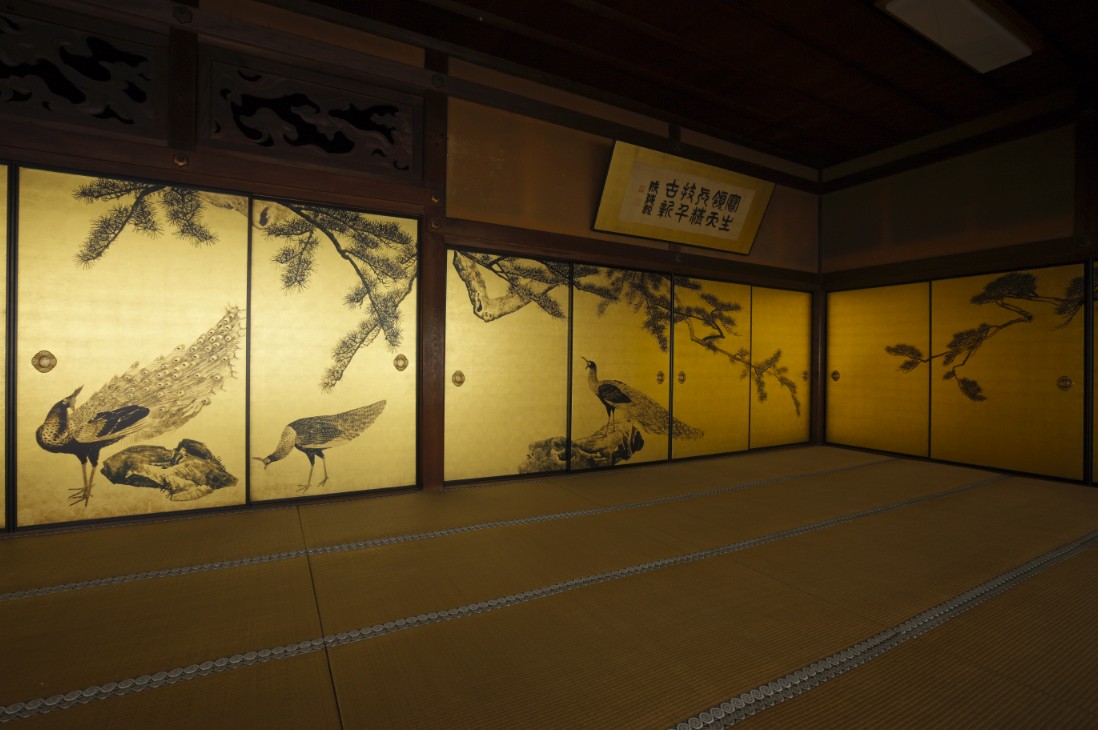 墨で木やクジャクが描かれた金色の襖の写真