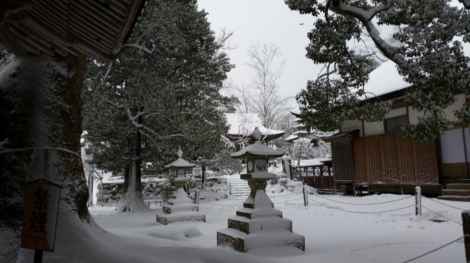雪の積もった境内にある灯篭の写真