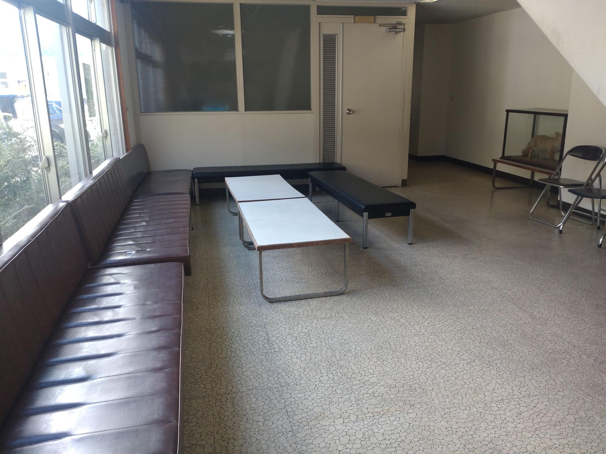 長椅子が複数設置され同じ高さのテーブルも配置された1階ロビーの写真