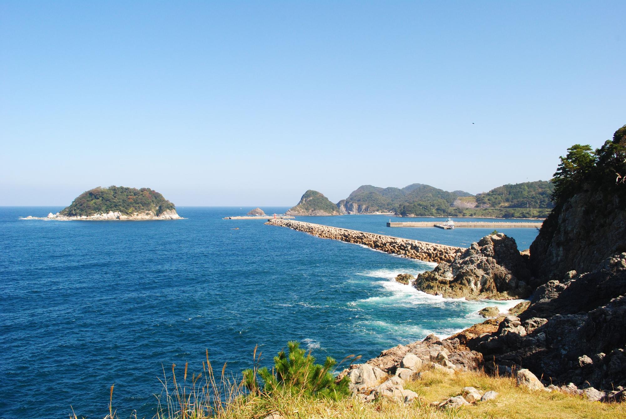 奥に島の見える海岸の写真