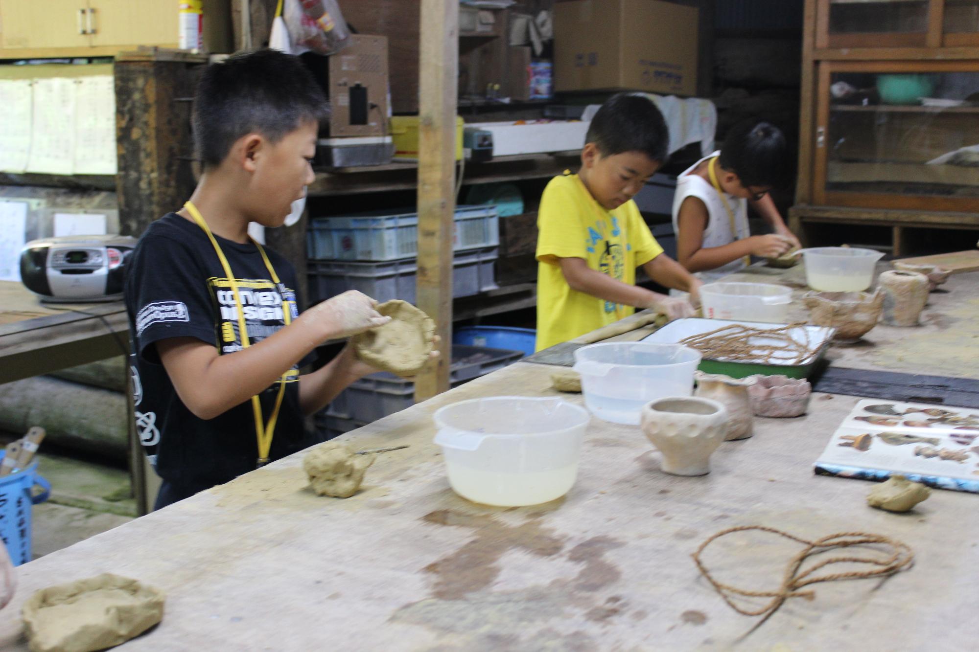 一生懸命に粘土をこねる子供たちの写真