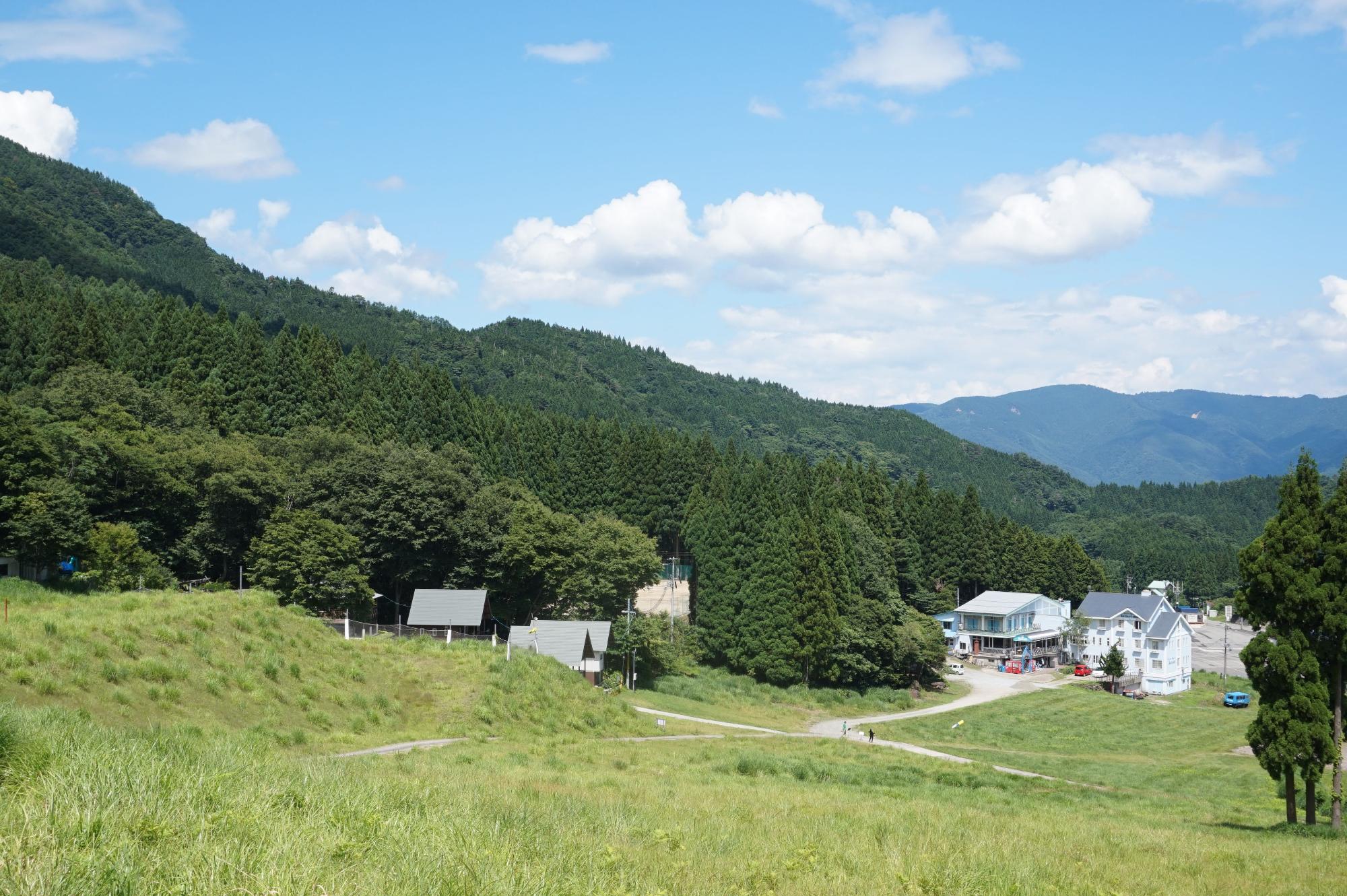 山の中腹にある広場に家が数軒建っている写真