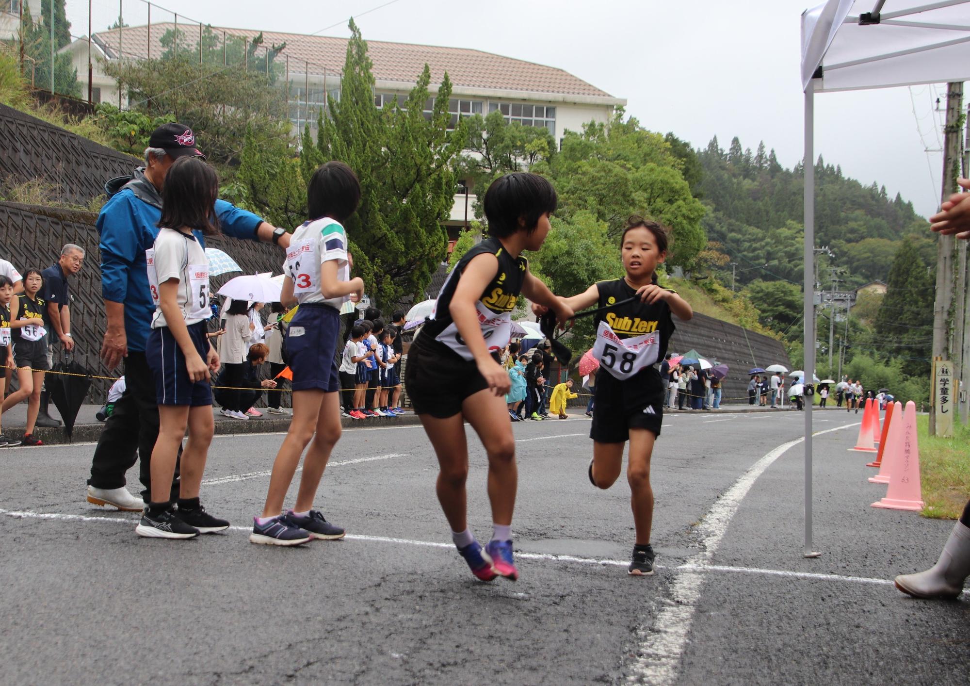 子供がバトンの受け渡しをしている写真