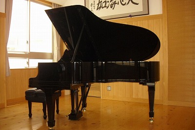窓から光が差し込む教室に黒いグランドピアノが置いてある写真