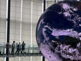 日本科学未来館館内に設置された大きな地球儀の展示の脇を通る生徒たちの写真