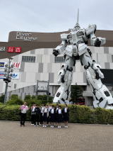 ダイバーシティ東京に展示されている白い塗装のガンダムの展示の前で集合写真を取る先生と生徒たちの写真