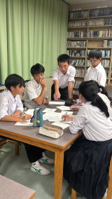 図書室の机を囲んでグループで話し合い活動をする生徒たちの写真