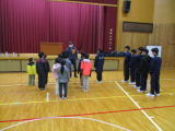 体育館で小学生と中学生が向かい合ってあいさつをしている写真