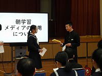 体育館で男子生徒と女子生徒が資料を見ながら互いに向き合って発表をしている様子の写真