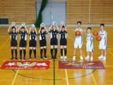 体育館のコート中央でバスケットボール部の選手たちが整列している写真