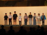ステージ上で私服姿の生徒たちが横一列に並んで発表している写真
