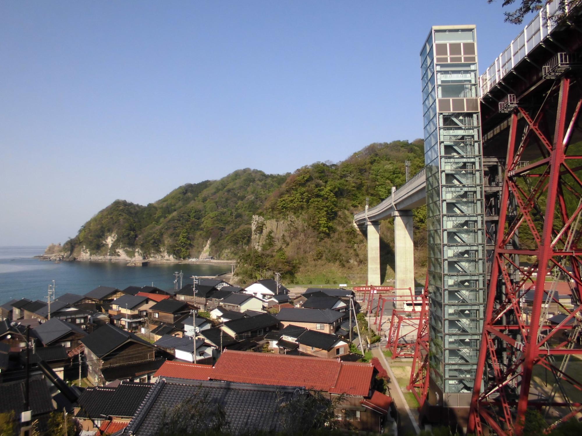 民家が建ち並んだ横に鉄橋がある写真