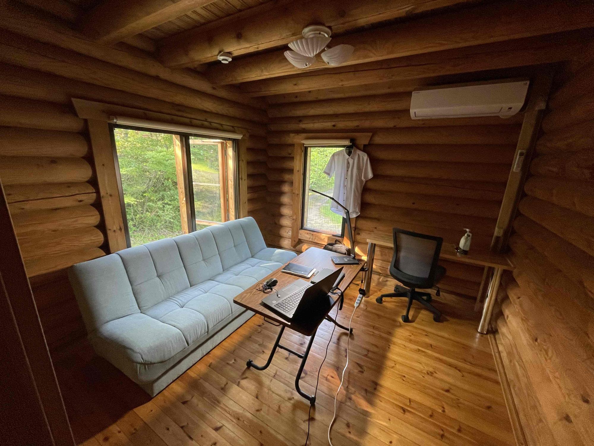 ログハウスの室内の写真。エアコンや長めのソファがある。