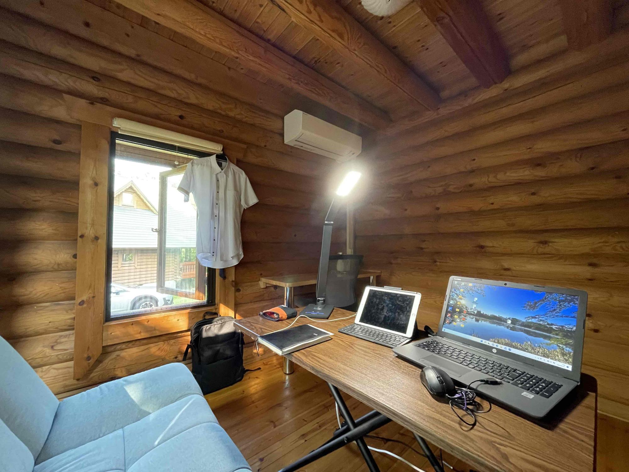 ログハウス内にあるワーク用デスクの写真。パソコンやタブレット端末が置いてある。