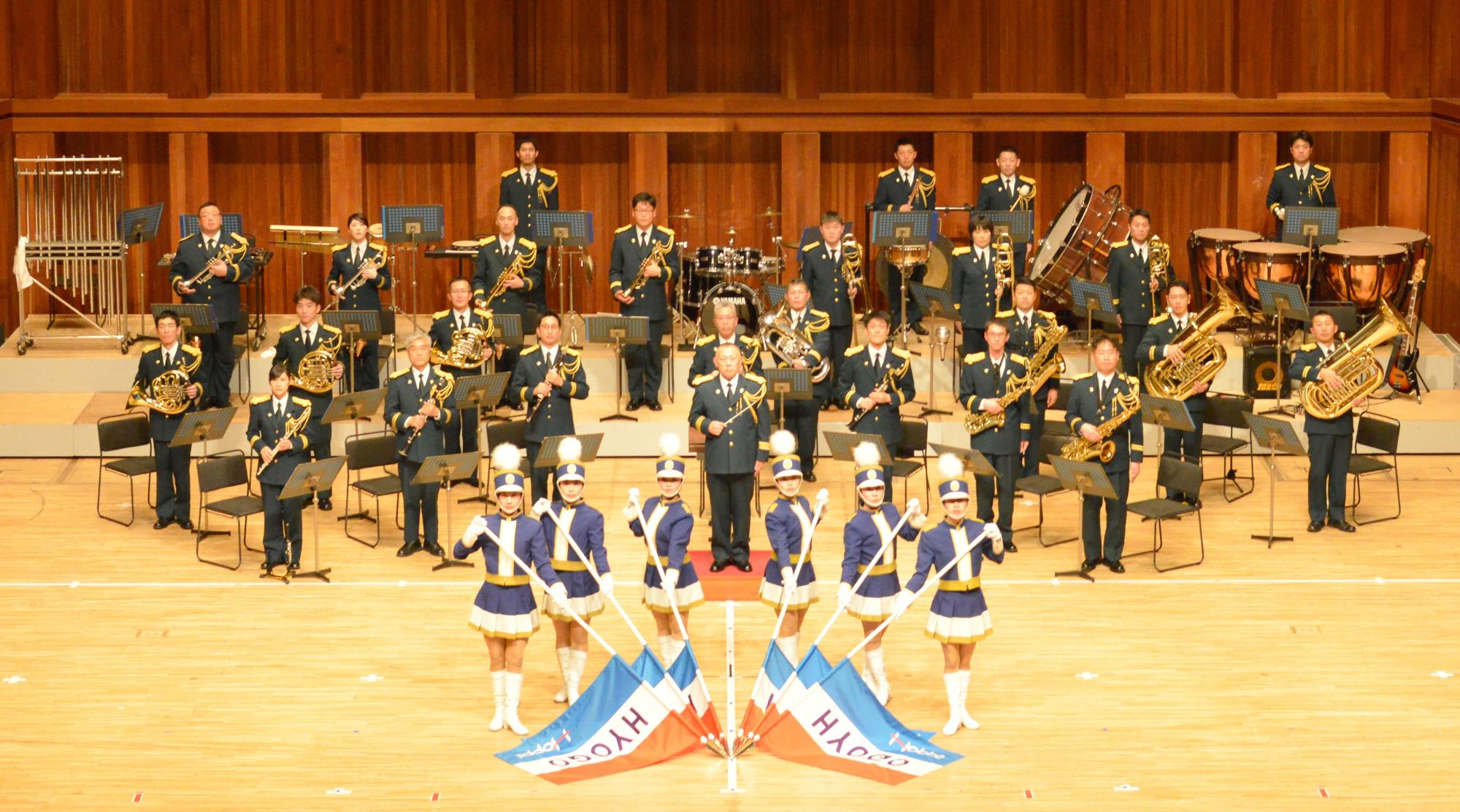 兵庫県警音楽隊とその前で旗を持った女性グループが一緒に写っている写真