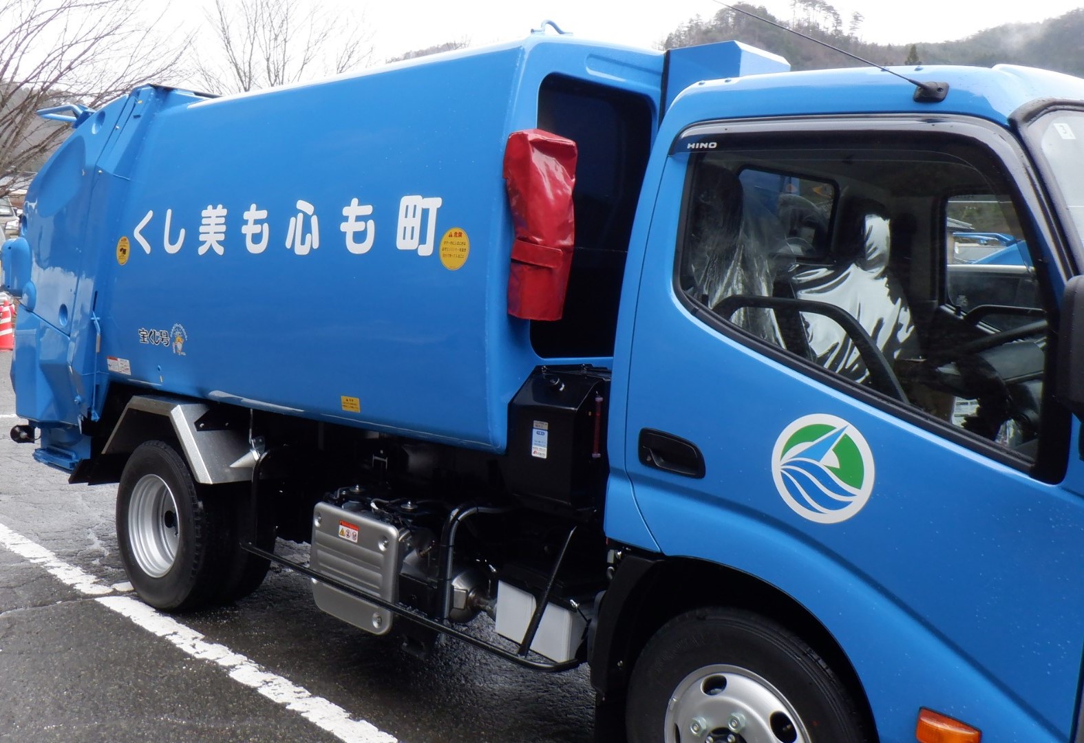 駐車場に町も心も美しくと書かれた青いごみ収集車が斜めから写されている写真