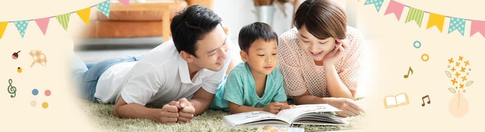 笑顔で絵本を読んでいる父母と男の子の写真。ガーランドや音符のイラストで装飾されている