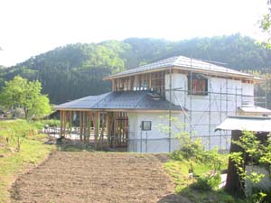 建築中の木造住宅と畑の画像