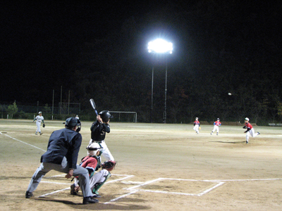 ナイター設備のあるグラウンドで野球をしている写真