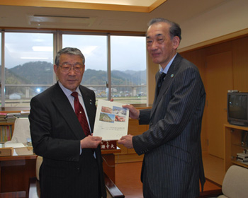 清水浩仁香美町観光連絡協議会会長と観光振興計画の報告書を手に持っている長瀬町長の写真