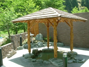 木でできた屋根の下に石でできた露天風呂がある写真