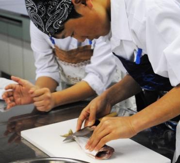 室内で児童が包丁を用いてアジをおろしている様子の写真