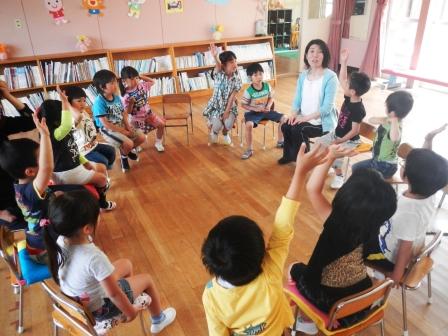 室内で椅子に座った児童たちが手を挙げている様子の写真