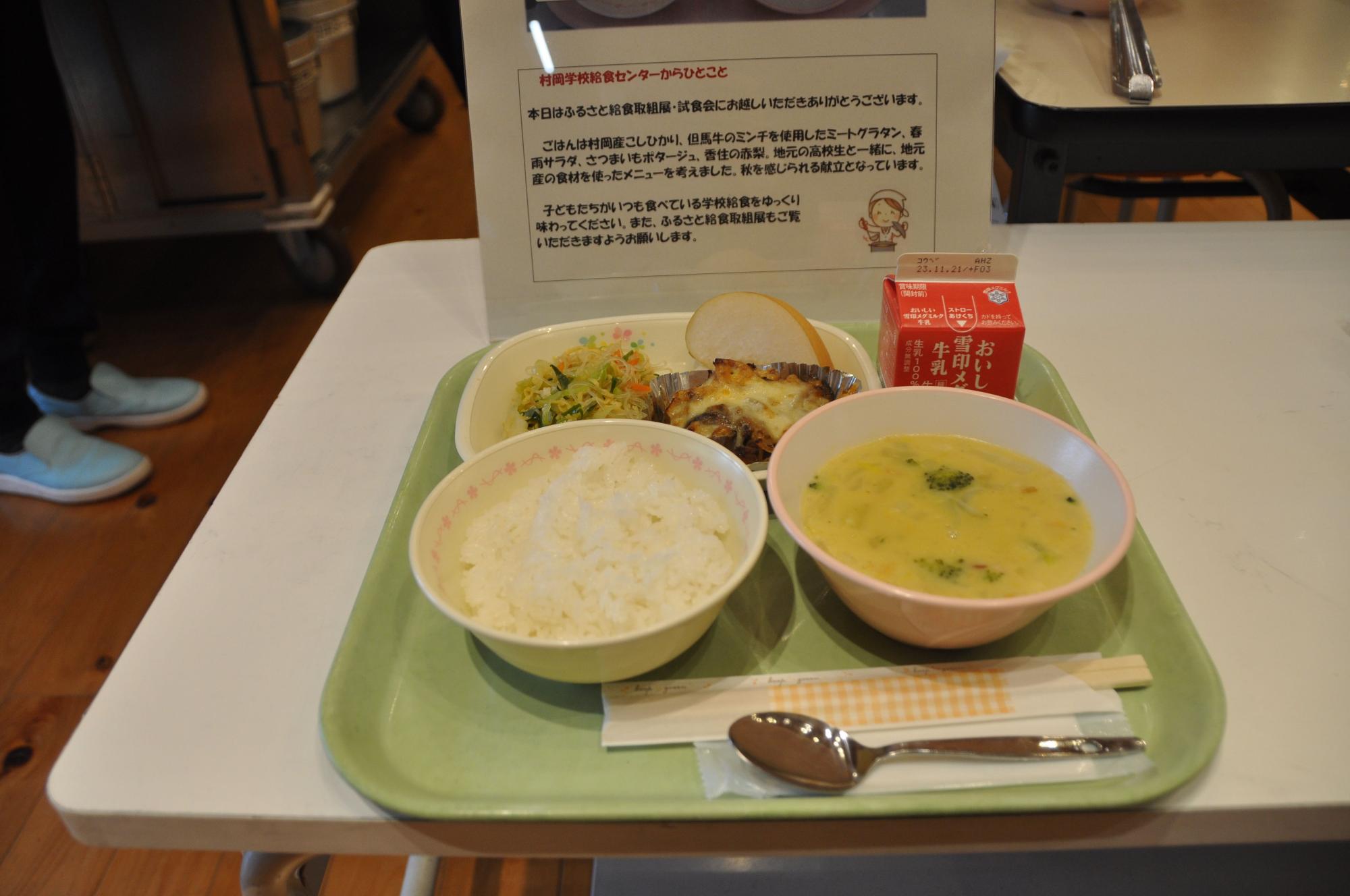 白い机の上に置かれているご飯とスープの給食の写真