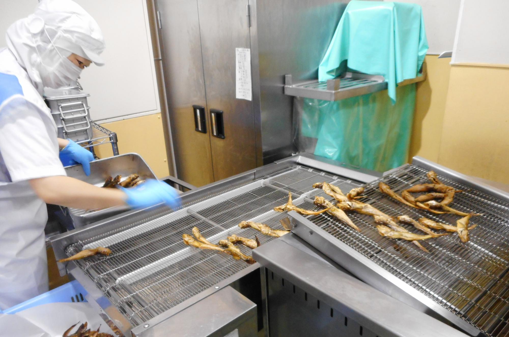室内で職員が魚を揚げている写真