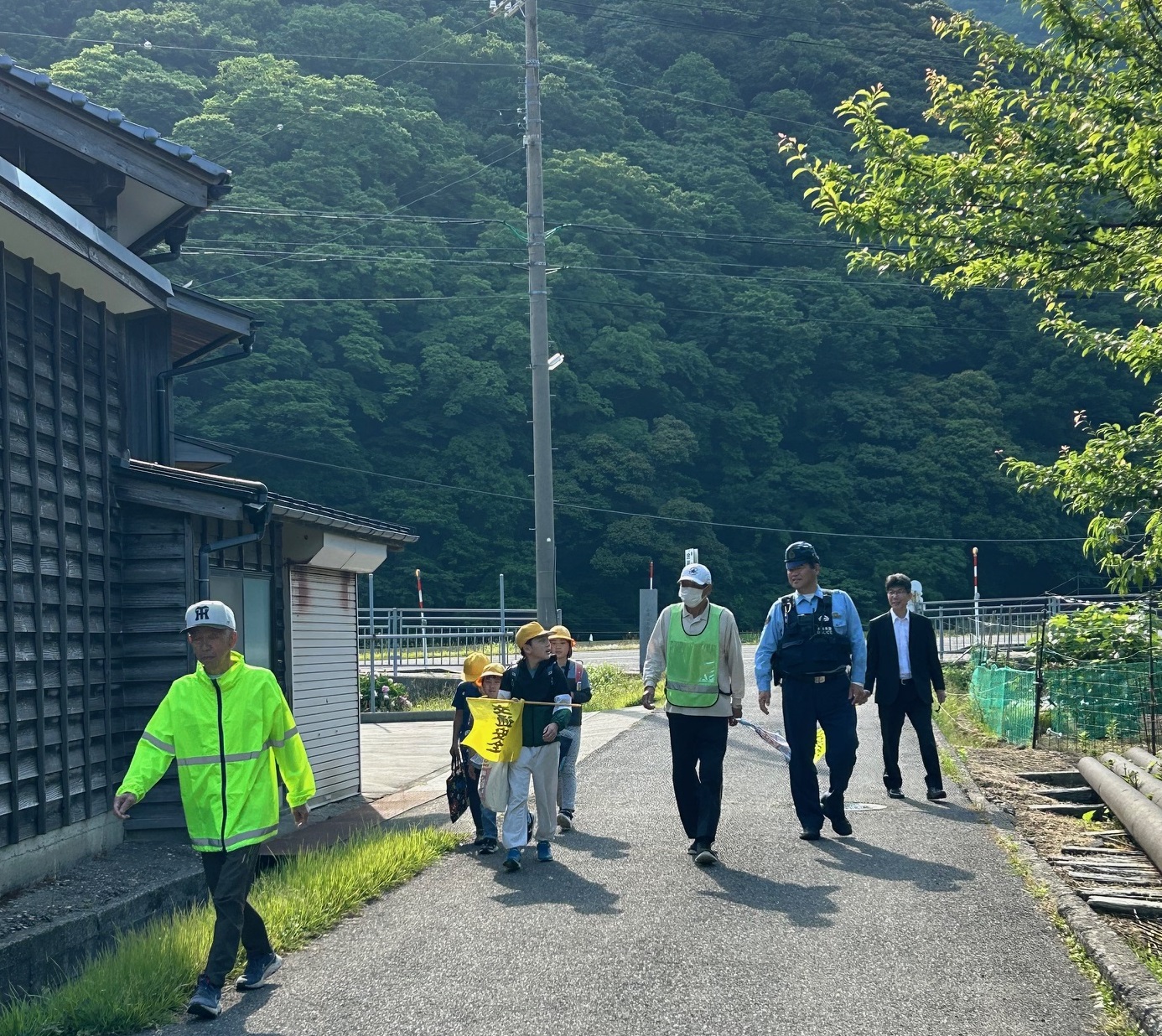 外で児童と大人たちが歩いている様子の写真