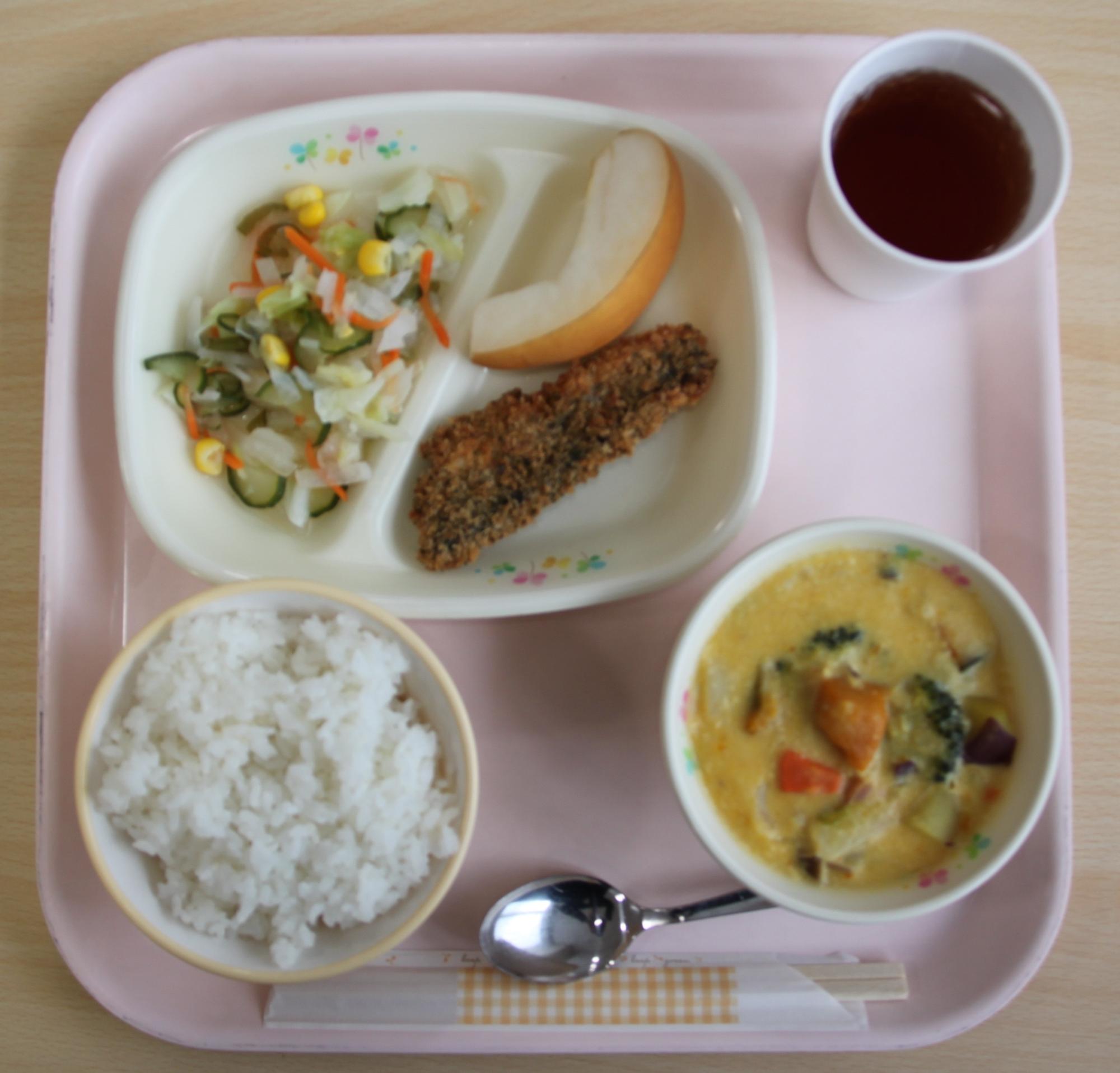 ご飯、シチュー、おかず、コップに注がれた飲み物が並んだ給食の写真