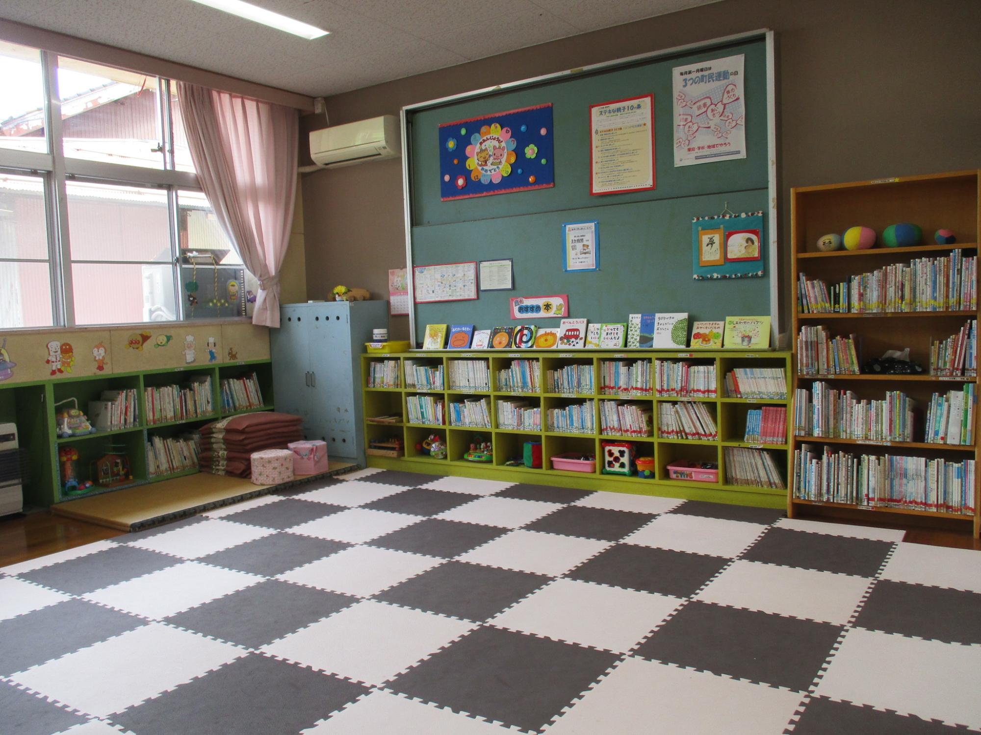 白黒のタイル状のマットが敷かれ、壁際に本棚が並んでいる部屋の写真