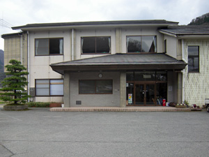 クリーム色の壁と灰色の屋根の二階建ての建物を正面から撮った写真