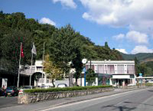 道路と山に挟まれた横長の大きな建物の写真