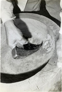 道具を使って臼を削っている白黒写真