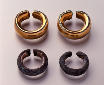 酷く錆びた輪状の耳飾り2点と1部が錆びた金色の輪状の耳飾り2点の計4点の写真
