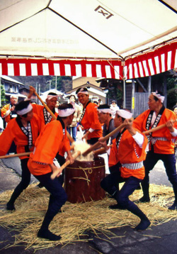 うすの上で餅を棒でつく7人のつき手たちの写真