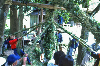 吊るされた太い綱から伸びる複数の細い綱をひっぱる人々の写真