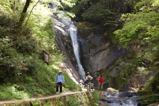滝に続く道を歩く人たちの写真
