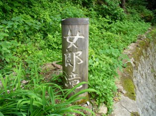 「女郎滝」と彫られた木製の支柱看板の写真